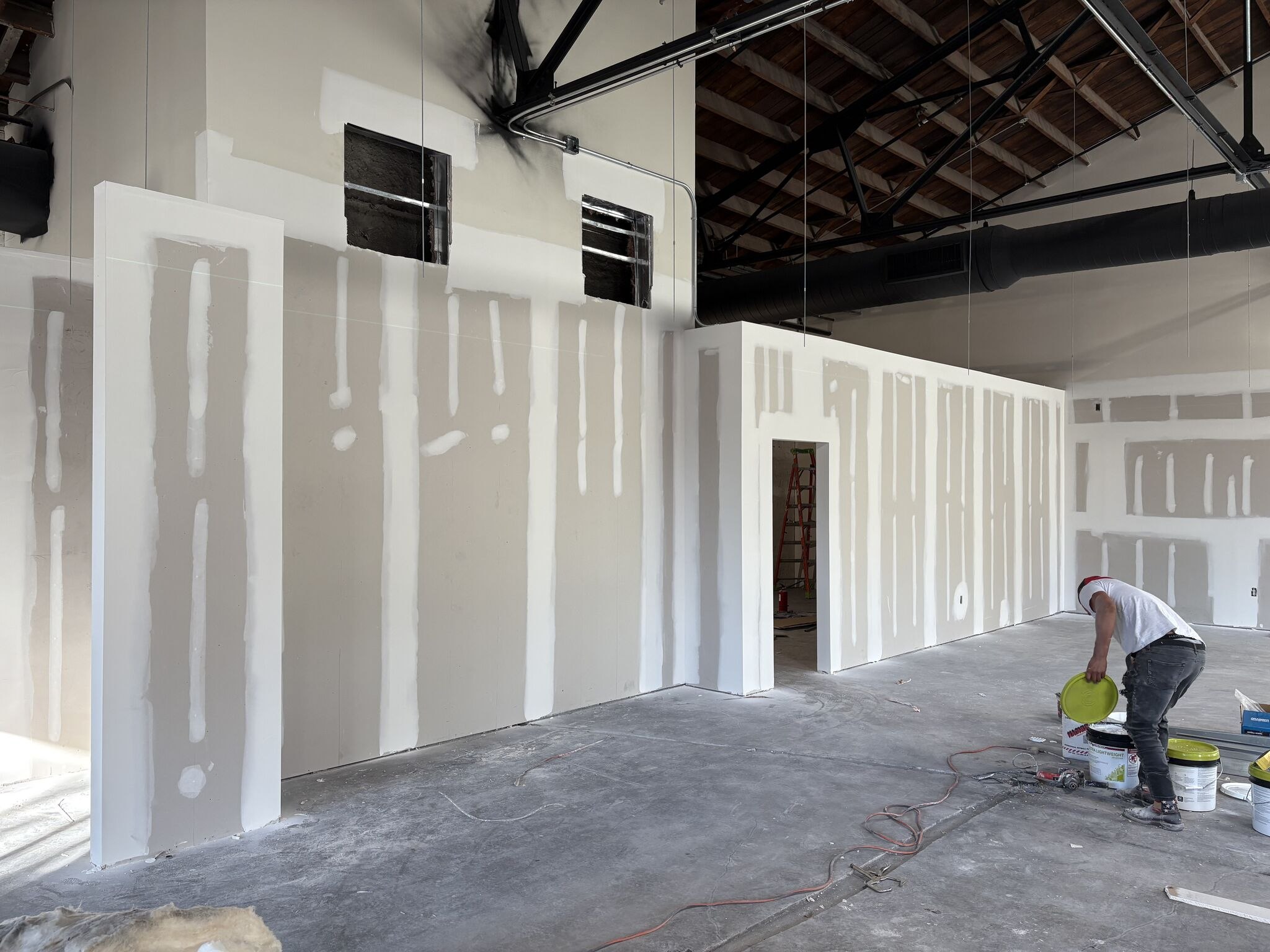 Drywall finishing on new partitions under the exposed roof steel